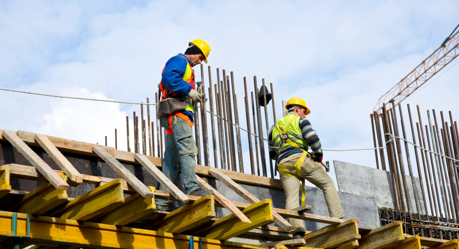 Ironworkers on yellow scaffolding with rebar and timber formwork